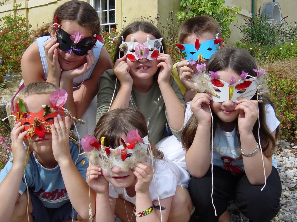 Children wearing paper masks decorated with natural materials